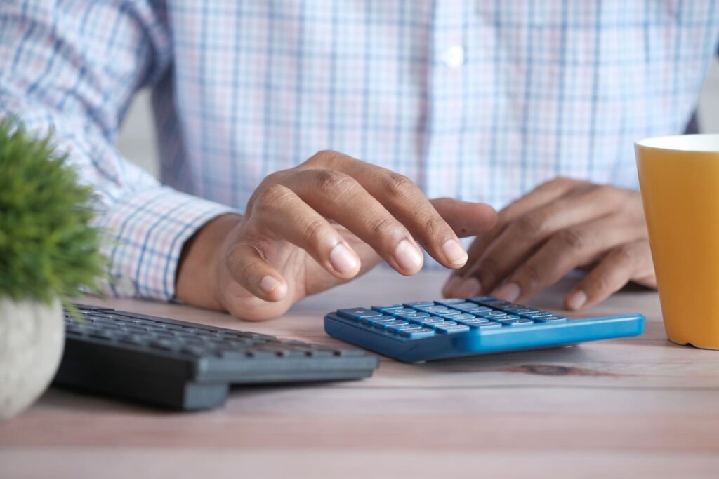 Um homem está fazendo os cálculos do reajuste do seu imóvel, usando uma calculadora de aluguel.