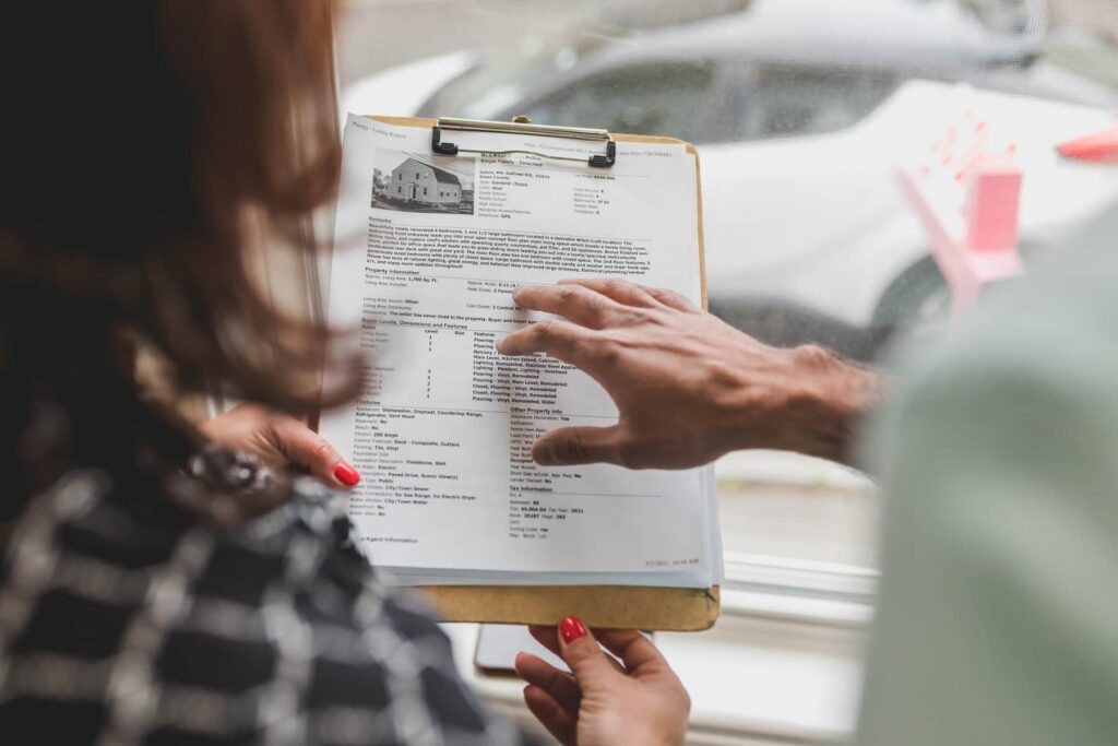 Uma mulher está mostrando uma prancheta com a descrição da corretagem imobiliária de um contrato de imóvel.