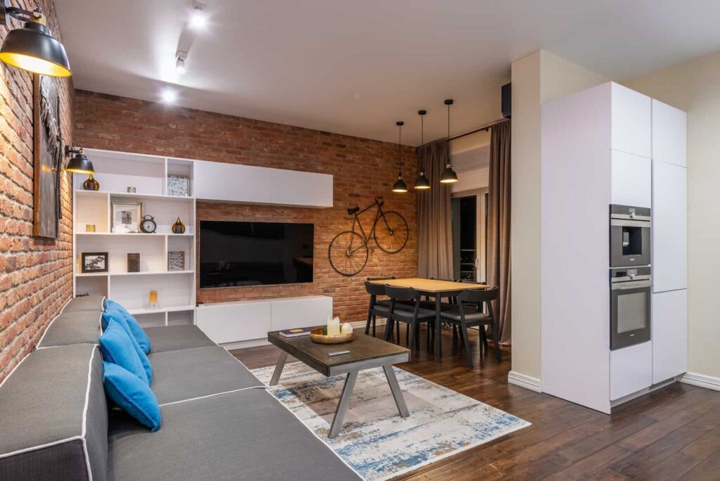 Uma sala de estar com tijolos aparentes está sendo usada como exemplo de estilo industrial na imagem.