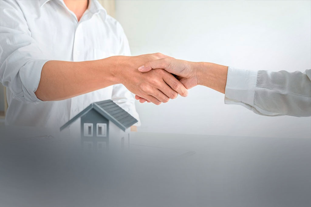 Um proprietário e um técnico em transações imobiliárias estão se cumprimentando na conclusão de um negócio.