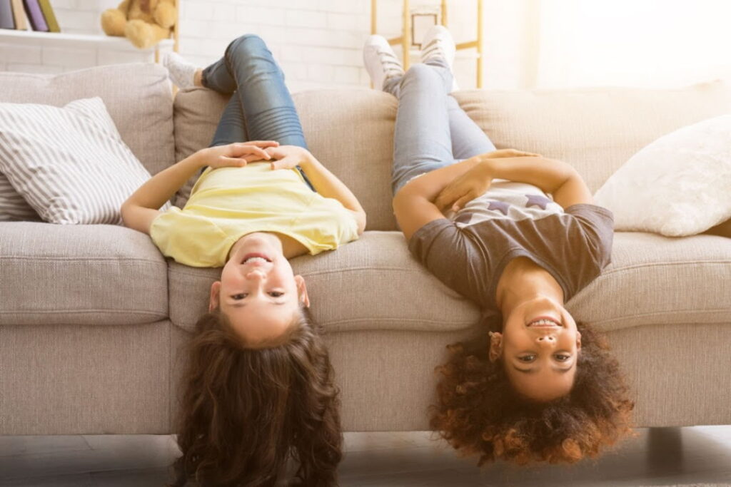 Duas crianças estão brincando em um sofá confortável em um apartamento.